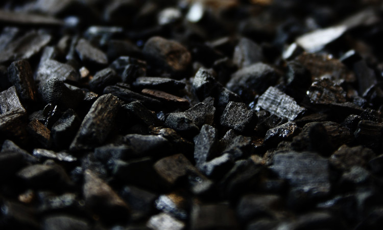 A pile of black charcoal with hints of copper, white, and gray