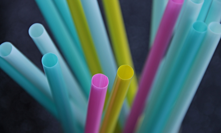 A cluster of blue, green, yellow, and purple straws that should be avoided during recovery from a tooth extraction