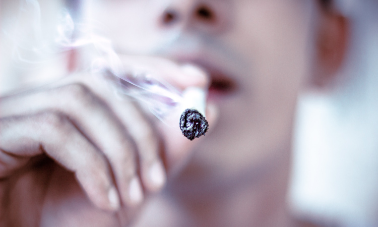 Closeup of man smoking a cigarette that causes oral cancer and lung cancer