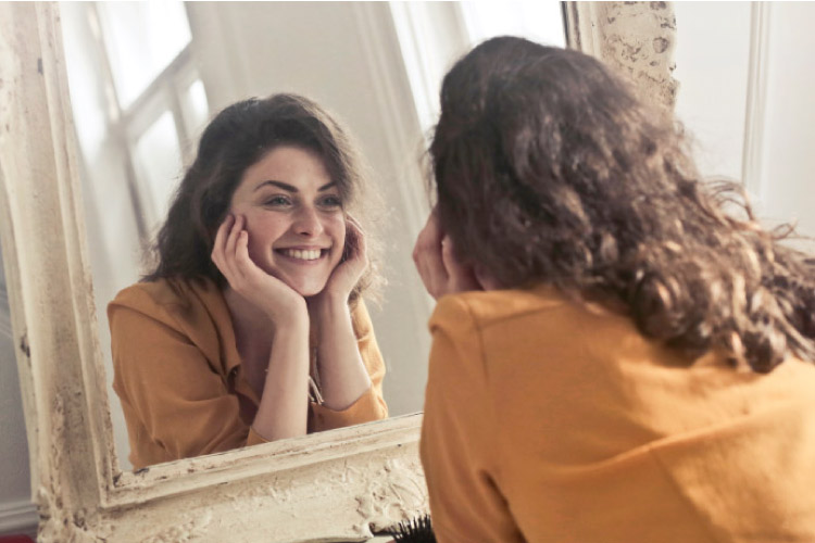 girl smiling into the mirror admiring her newly whitened teeth