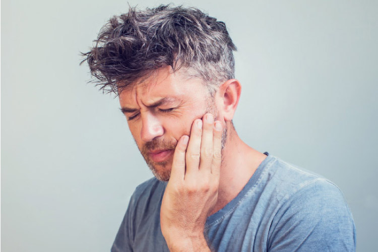 man holds his jaw in pain from a dental emergency