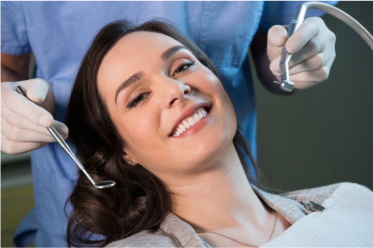 young woman smiles as she sits in the dentist's chair for her regular appointment