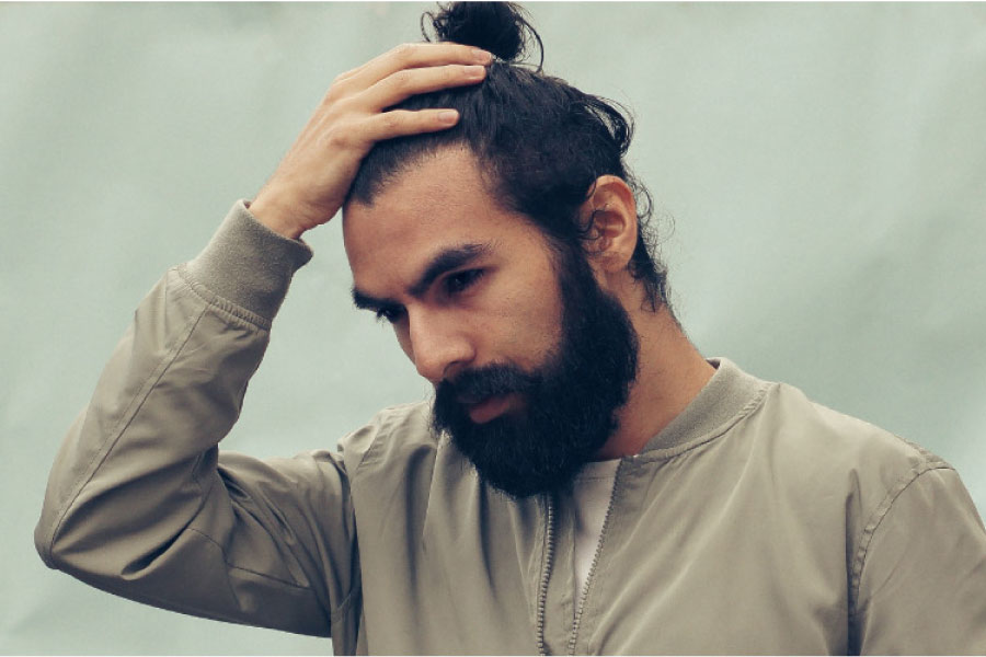 bearded man holds his head with a stress headache