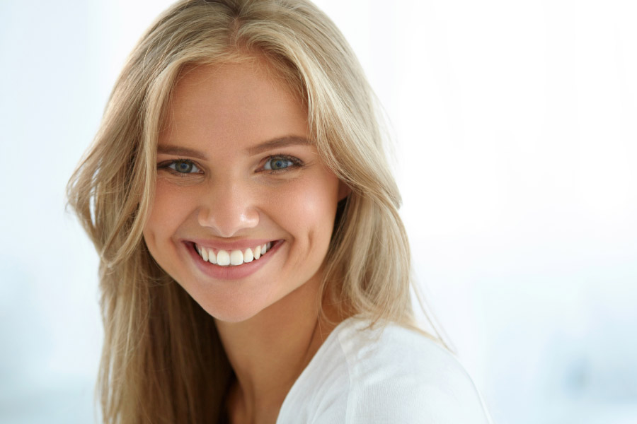 young woman smiles after getting professional teeth whitening treatments