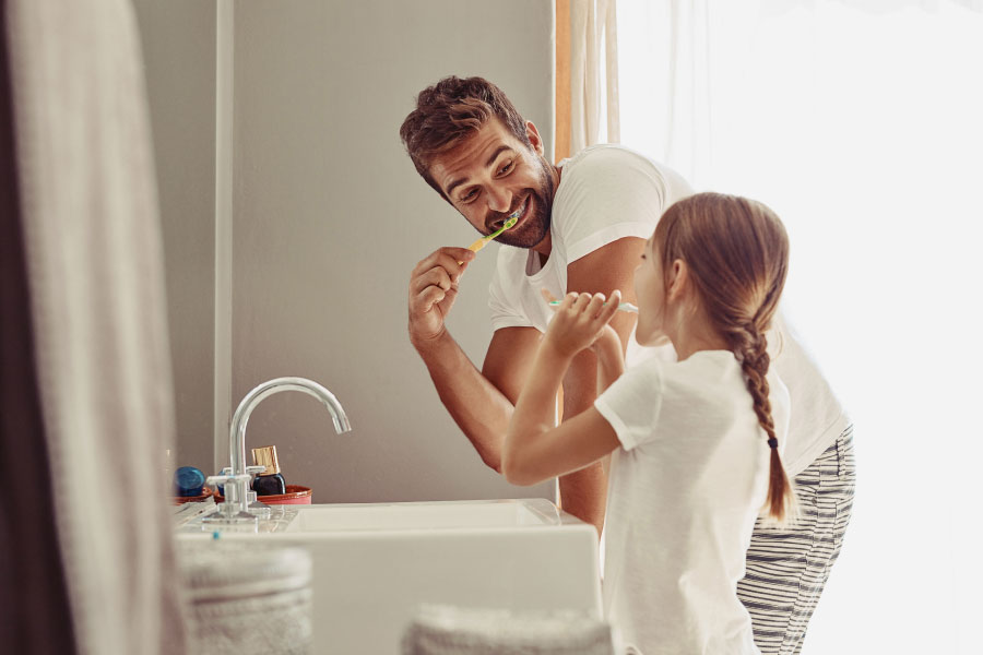 father and his young daughter brush their teeth together