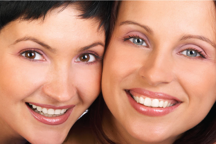 close up of two woman smiling showing off their whit teeth