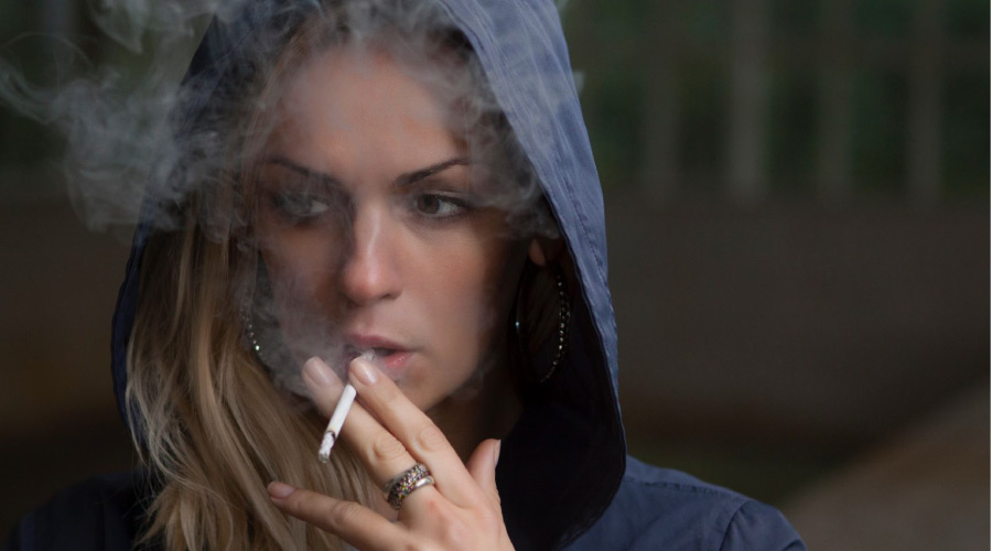 woman wearing a hoodie smoking a cigarette