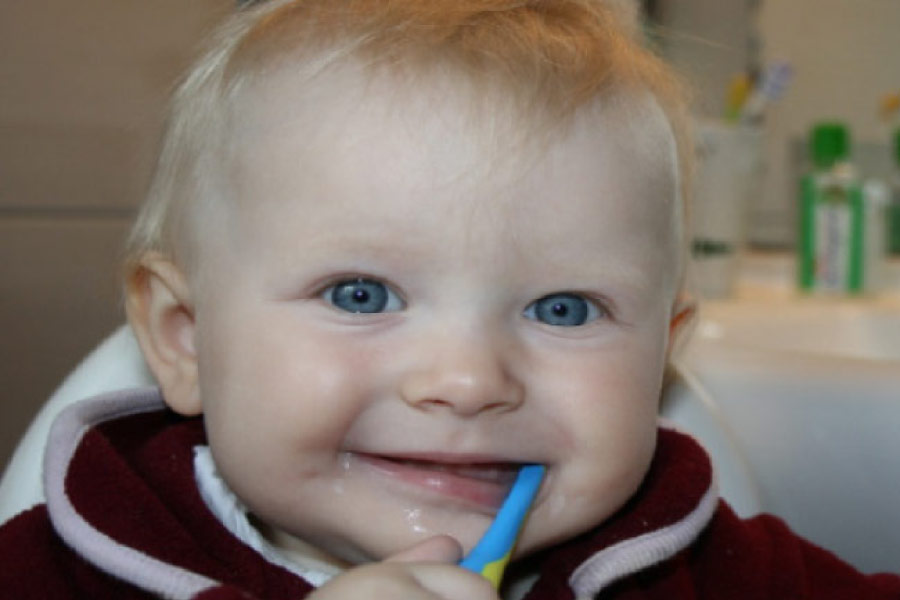 baby blue eyed boy with a toothbrush in his mouth